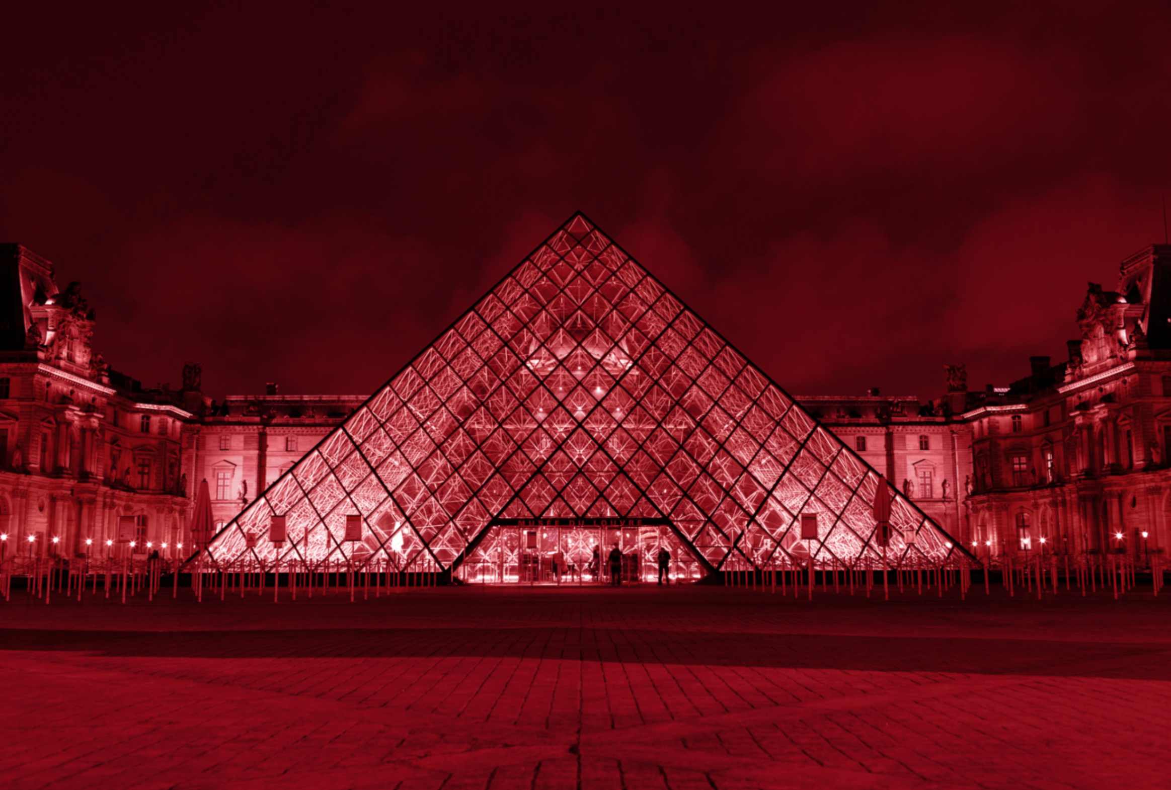 a large glass pyramid-shaped building iluminated at night.