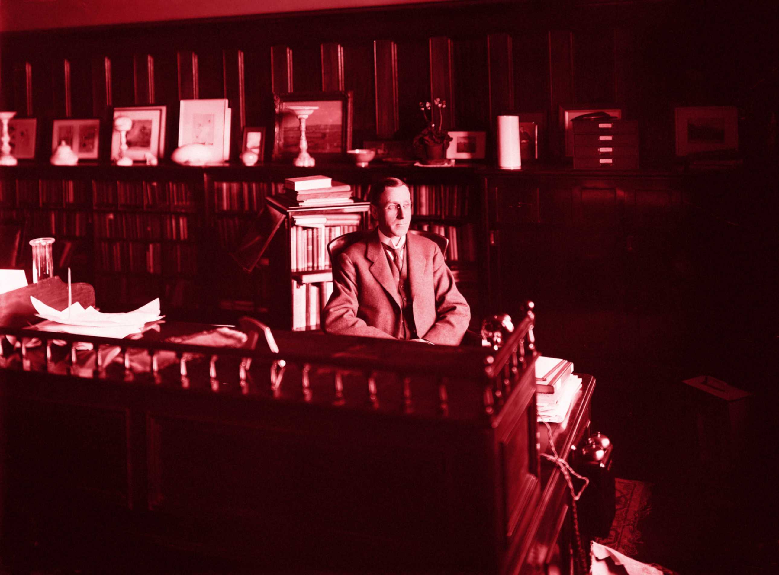 a professor sitting in his office surrounded by books.